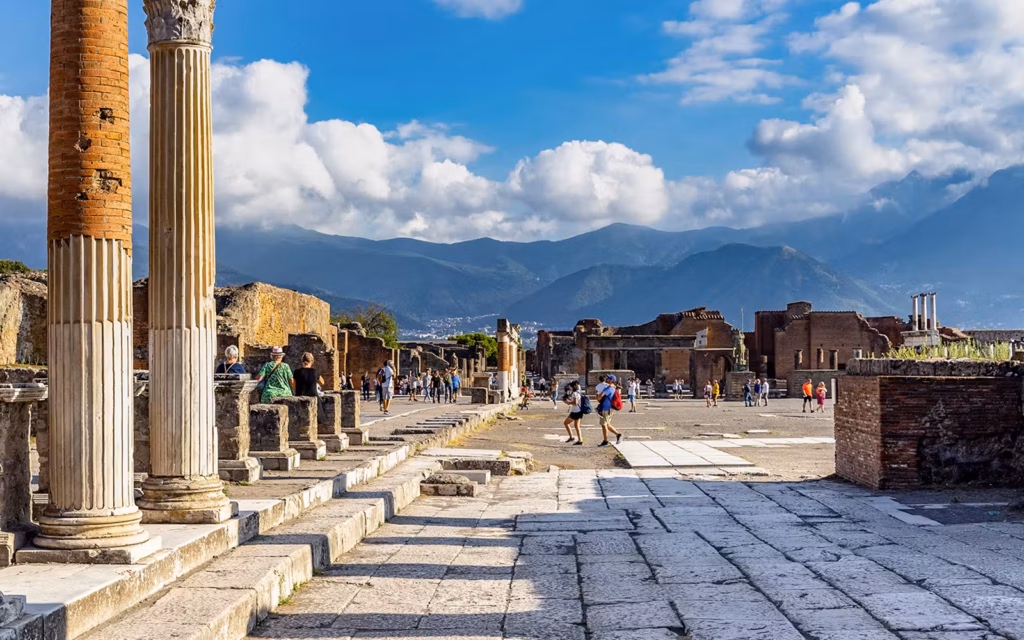 Ancient Roman ruins of Pompeii with tourists exploring old stone streets and columns.